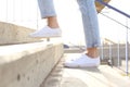 Profile of woman legs wearing sneakers walking up stairs