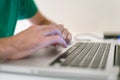 Profile detail shot of a mans dynamic hands using a laptop on a whitetable Royalty Free Stock Photo