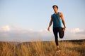 Profile of a fit, abs, sportive young man doing stretching exercises with feet, isolated on a sunset sky background. Royalty Free Stock Photo