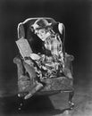 Profile of a girl sitting in an armchair holding a book