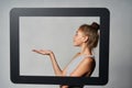 Profile of girl standing behind digital tablet frame and showing blank copy space on her palm