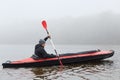 Profile of man floating on lake in kayak, looking concentrated on his way, rowing boat in cold cloudy day, water sport, guy in