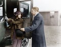 Profile of a man helping a young woman board a car