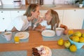 Profile of mom and daughter in the kitchen biting the donut on both sides. cute family photo. dressed in white tshirts
