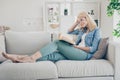 Profile photo of attractive aged mature homey lady sitting comfy sofa couch barefoot reading interesting historic novel Royalty Free Stock Photo