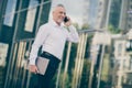 Profile photo of optimistic grey hair old business man talk telephone hold laptop wear white shirt outdoors near work Royalty Free Stock Photo