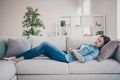 Profile photo of pretty lady suffering from pms holding hands on hurted belly lying sofa trying to relax wearing jeans