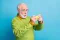 Profile photo of shocked grandpa hold telephone watch movie wear glasses green pullover isolated blue color background Royalty Free Stock Photo