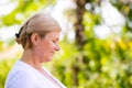 The profile photo of a sporty blonde woman being in the park resting after fitness exercises and looking smiley.