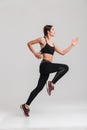 Profile picture of well-built athletic female runner in sportswear training, isolated along gray background Royalty Free Stock Photo