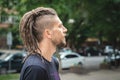 Profile portrait of a caucasian man with dreadlocks, beard and sidecut on a summer outdoor