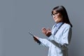 Profile portrait of female doctor holding clipboard on gray background, copy space Royalty Free Stock Photo