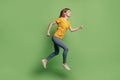 Profile portrait of funny inspired active lady jump run wear yellow t-shirt jeans sneakers on green background