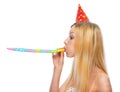 Profile portrait of girl in cap blowing in party horn blower