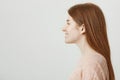 Profile portrait of gorgeous feminine redhead girl with freckles smiling and standing against gray background. Woman in Royalty Free Stock Photo