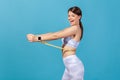 Profile portrait happy slim woman in white sportswear holding on waist tape measure and looking at camera with satisfaction and Royalty Free Stock Photo