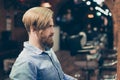 Profile portrait of harsh stylish red bearded man in a barber sh