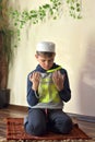Profile portrait image of young cute muslim boy wearing traditional islamic prayer hat cap.