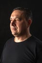 Profile portrait of man set against dark backdrop. Studio shot with subtle lighting, highlighting strong features, calm, Royalty Free Stock Photo