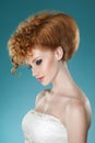 Profile portrait of a red hairred woman with hairdressed and speckle, wearing a wedding dress, over blue background