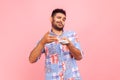 Profile portrait of self confident young adult handsome man with beard scattering dollars with proud facial expression, rich