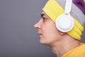 Profile portrait of serious concentrated man wearing yellow hoodie, beanie hat headphones standing isolated over gray background, Royalty Free Stock Photo