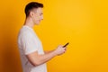 Profile portrait of smart cool guy hold telephone look screen on yellow background