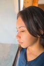 Profile portrait of a woman looking out of a window in her home or hotel room Royalty Free Stock Photo