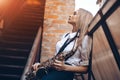Profile portrait young attractive girl in white shirt with a saxophone - outdoor in old town. young woman with sax thinking a Royalty Free Stock Photo