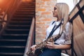 Profile portrait young attractive girl in white shirt with a saxophone - outdoor in old town. young woman with sax thinking a Royalty Free Stock Photo