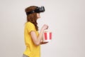 Profile portrait of young brown haired woman in VR headset watching movie with popcorn, wearing