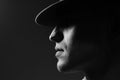 Profile portrait of a young man in a hat standing over dark gray background. Close up. Classic style. Copy-space. in bright ligh Royalty Free Stock Photo