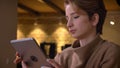 Profile portrait of young short-haired woman smilingly watching into tablet in office.