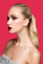 Profile portrait of young woman with perfect makeup with bare shoulders, over bright red background. Royalty Free Stock Photo