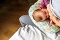 Profile portrait of a young woman breastfeeding a child using a special breastfeeding pillow for newborn babies