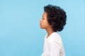 Profile of pretty nice little boy with stylish curly hair in T-shirt looking to side with serious attentive face