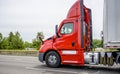 Profile of red big rig day cab semi truck with dry van semi trailer driving on the straight road Royalty Free Stock Photo
