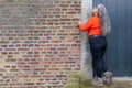 Profile of an senior Latin American woman standing and leaning against brick wall next to closed wooden door Royalty Free Stock Photo