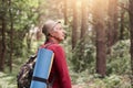 Profile of senior man looking aside attentively, going camping, wandering in forest, uniting with nature, having backpack and