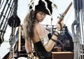 Profile of a Pirate female captain standing on the deck of her ship with pistol in hand.