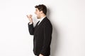 Profile shot of handsome businessman in black suit talking on speakerphone, smiling and looking happy, recording voice Royalty Free Stock Photo