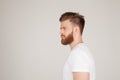 Profile shot of handsome male with trendy hairdo and beard, looks aside with serious expression, has thick red beard, isolated Royalty Free Stock Photo