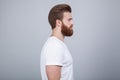 Profile shot of handsome male with trendy hairdo and beard, looks aside with serious expression, has thick red beard, Royalty Free Stock Photo