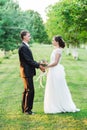 Profile shot of a yound wedding couple in a summer dawn garden looking at the beloved holding hands