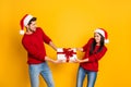 Profile side of angry couple pull package wear red sweater pullover santa claus cap denim jeans isolated over yellow