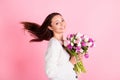 Profile side photo of charming sweet cute young woman hold flowers fly hair isolated on pastel pink color background Royalty Free Stock Photo