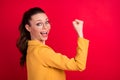 Profile side photo of cheerful amazed happy young woman raise fist winner isolated on red color background