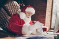 Profile side photo of excited santa claus sit table x-mas christmas decoration house indoors get receive letter read Royalty Free Stock Photo