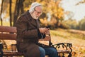 Profile side photo of modern white grey hair old man sit bench in autumn october trees park rest relax weekend use Royalty Free Stock Photo