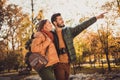 Profile side photo of positive couple go in autumn september park guy point finger sunshine sky wear coats Royalty Free Stock Photo